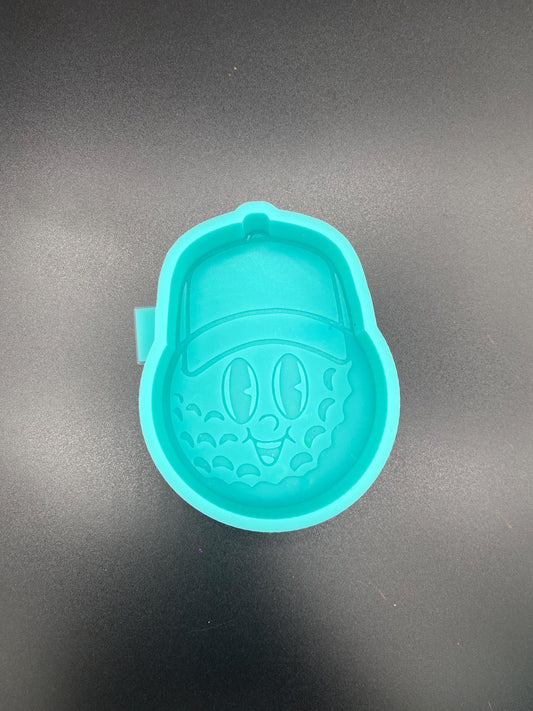 May include: Teal silicone mold of a cartoon golf ball wearing a baseball cap. The golf ball has a smiling face with simple eyes and a wide mouth. The mold is designed for creating resin crafts or other similar projects.  The mold is a bright teal color and shows fine details of the golf ball texture and facial features. The baseball cap sits atop the golf ball, adding to the whimsical design.